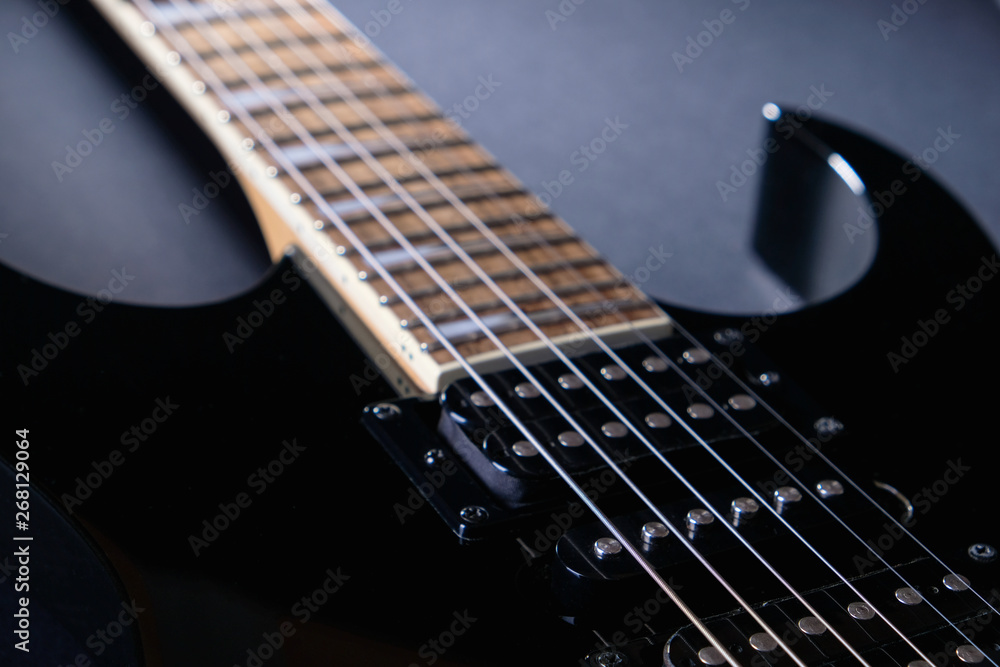 Body and neck of black electric guitar. Close up detail. On dark background Body and neck of black electric guitar. Close up detail. On dark background