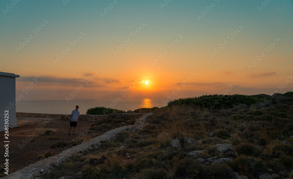sunset over the sea and walking young man