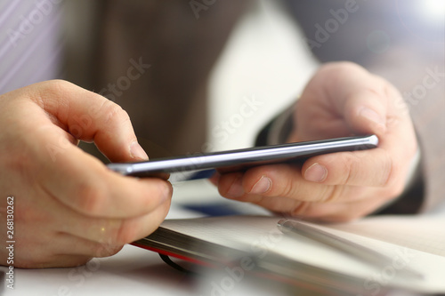 Male arm in suit hold phone and silver pen at workplace closeup. Read news mania send sms chat addict use electronic bank modern lifestyle job plan colleague share blog tweet web application search