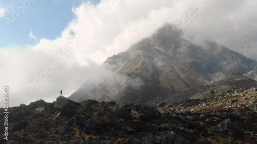 4k aerial side fly with man on rocks in front of a mountain in Langtang Valley in Nepal