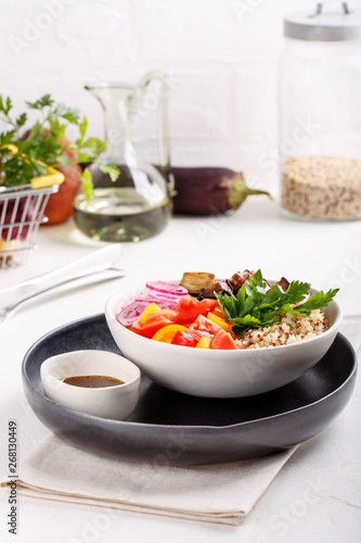 Quinoa salad with roasted eggplant, fresh tomatoes and red onion. Vegan or vegetarian food. Healthy salad in bowl served on white table.