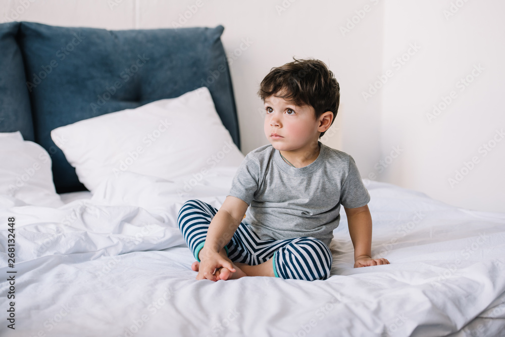 cute kid with barefoot sitting on bed at home cute kid with barefoot sitting on bed at home
