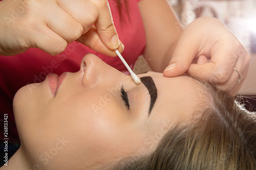 Young woman having professional eyebrow correction procedure in beauty salon