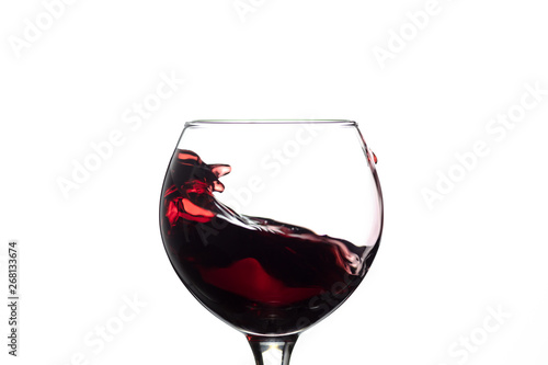 Red wine splash into glass on white background