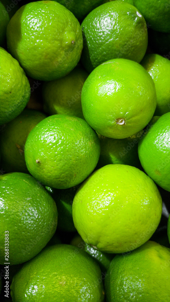 Closeup photo of green limes with GMO lying on counter at store. Closeup texture or pattern of fresh ripe fruits. Beautiful food background Closeup photo of green limes with GMO lying on counter at store. Closeup texture or pattern of fresh ripe fruits. Beautiful food background
