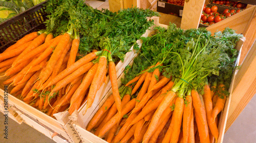 Beautiful image of fresh organic carrots with GMO in wooden crated at vegetable store. Closeup texture or pattern of fresh ripe vegetables. Beautiful food background