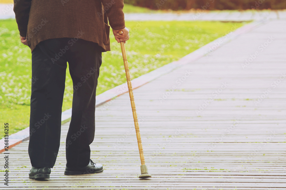 elderly old man with walking stick stand on footpath sidewalk crossing the street alone roadside in public park. concept senior across the street. soft focus elderly old man with walking stick stand on footpath sidewalk crossing the street alone roadside in public park. concept senior across the street. soft focus