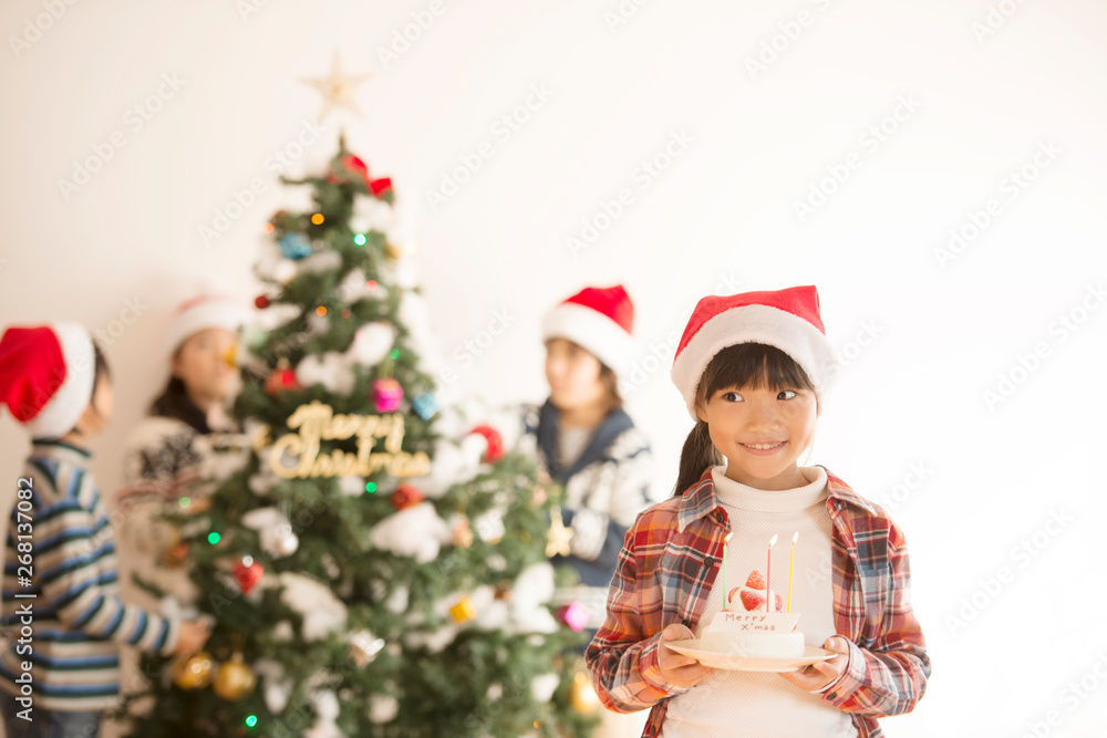 クリスマスツリーの前でケーキを持つ女の子