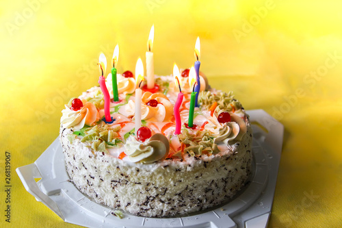 Traditional sweet birthday cake with colorful candles.