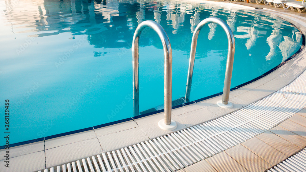 Closeup image of metal handrails on staircase at outdoor swimming pool Closeup image of metal handrails on staircase at outdoor swimming pool
