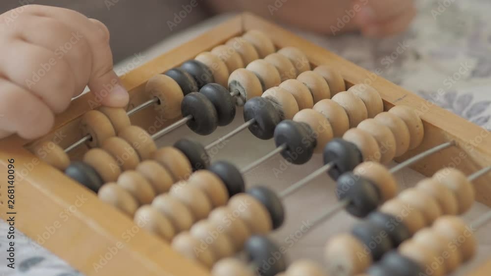 Toddler is counting with wooden abacus. Baby is playing with old wooden device. Child is learning to count. Toddler is counting with wooden abacus. Baby is playing with old wooden device. Child is learning to count.
