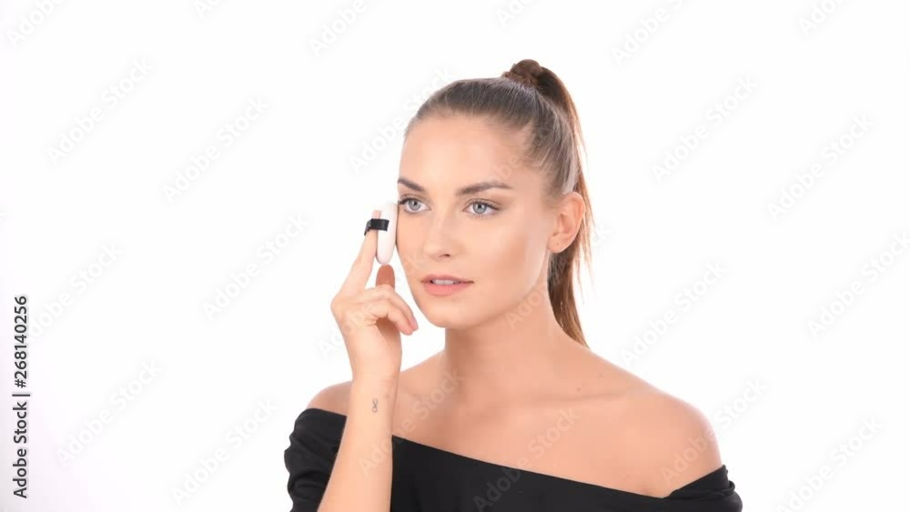 Beauty concept. Young woman applying blusher on her face with powder puff. Beauty concept. Young woman applying blusher on her face with powder puff.
