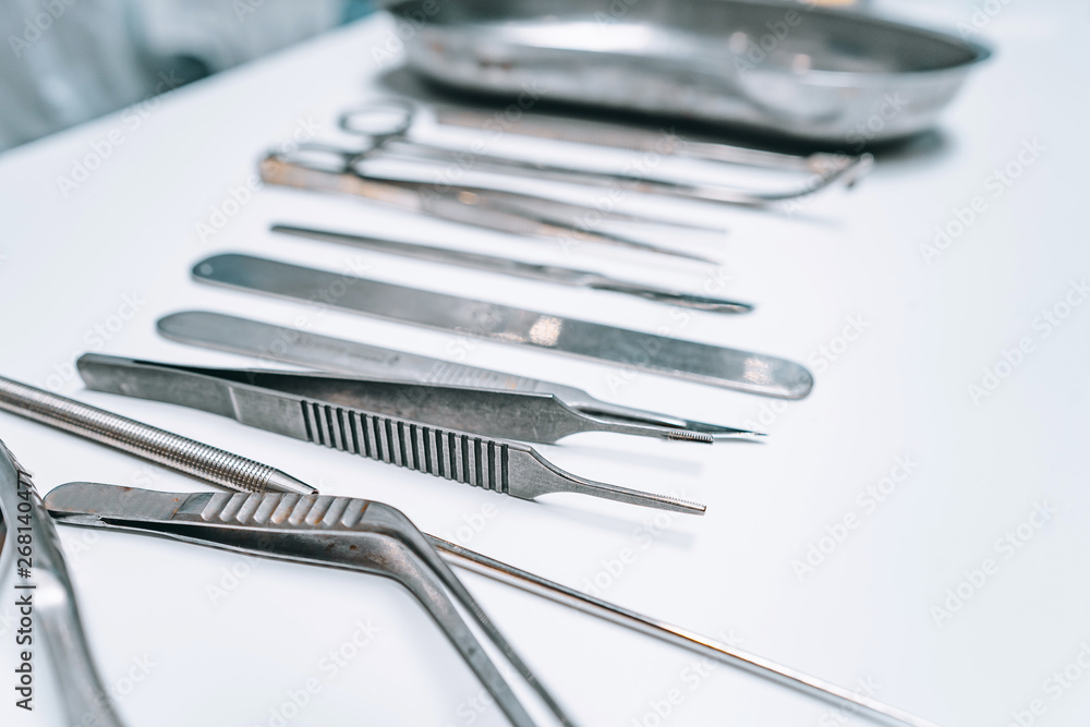 Several surgical instruments lie on a white table Several surgical instruments lie on a white table