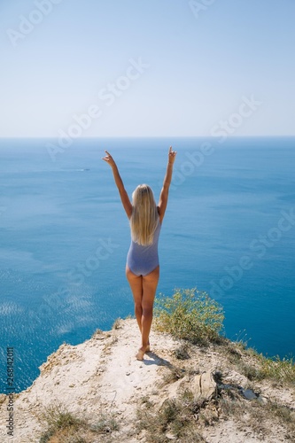 young woman in swimsuit with long blond hair on the beach with blue sea and sky
