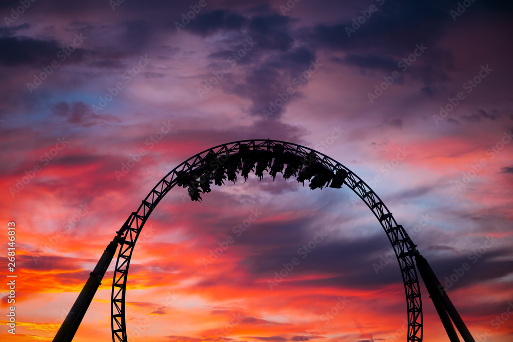 Silhouette of people having fun on a roller-coaster in an amusement park at sunset. Adrenalin concept. - obrazy, fototapety, plakaty 