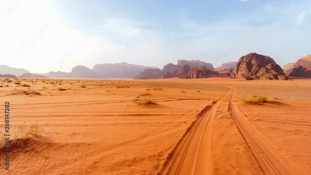 Wadi Rum desert, Jordan, The Valley of the Moon. Orange sand, haze, clouds. Designation as a UNESCO World Heritage Site. National park outdoors landscape. Offroad adventures travel background. - obrazy, fototapety, plakaty 