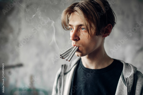 Young junkie with many cigarettes in his mouth