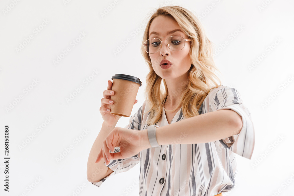 Portrait of charming serious woman wearing glasses holding paper cup and looking at wristwatch Portrait of charming serious woman wearing glasses holding paper cup and looking at wristwatch