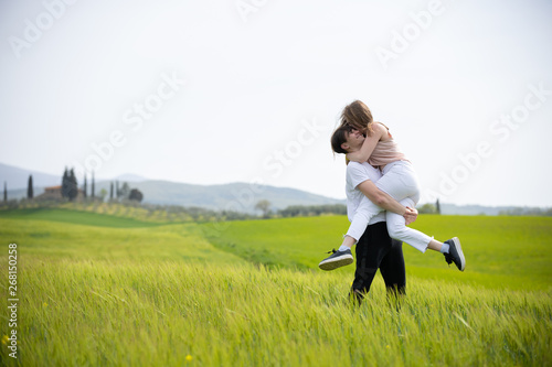 A young happy smiling couple on a green meadow. A man holding his girlfriend on hands