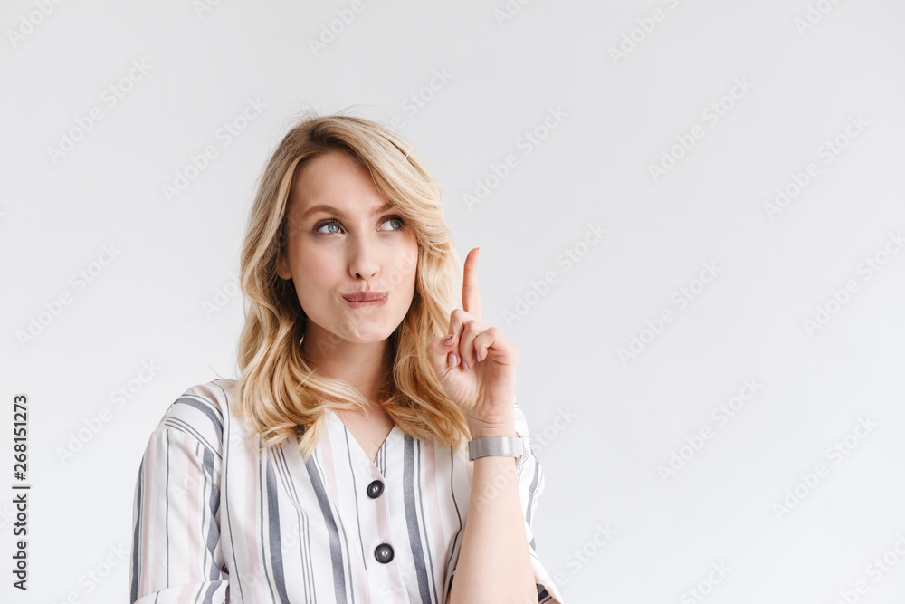 Portrait of young blond woman wearing casual clothes looking at copyspace and pointing finger upward Portrait of young blond woman wearing casual clothes looking at copyspace and pointing finger upward