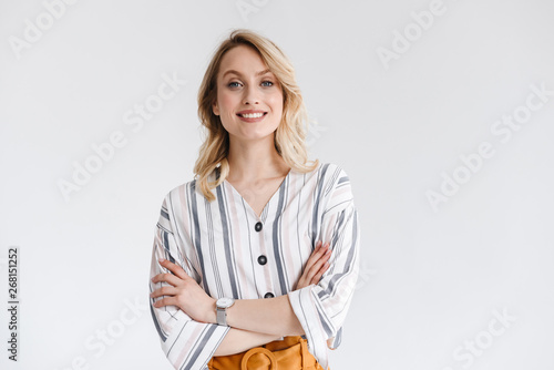 Portrait of blond young woman wearing casual clothes smiling at camera with arms crossed