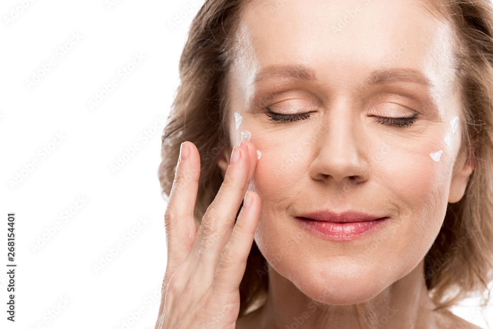 mature woman applying cosmetic cream on face Isolated On White mature woman applying cosmetic cream on face Isolated On White