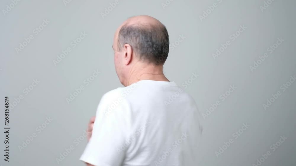 Senior man stands with his back to the camera and turns looking irritated Senior man stands with his back to the camera and turns looking irritated