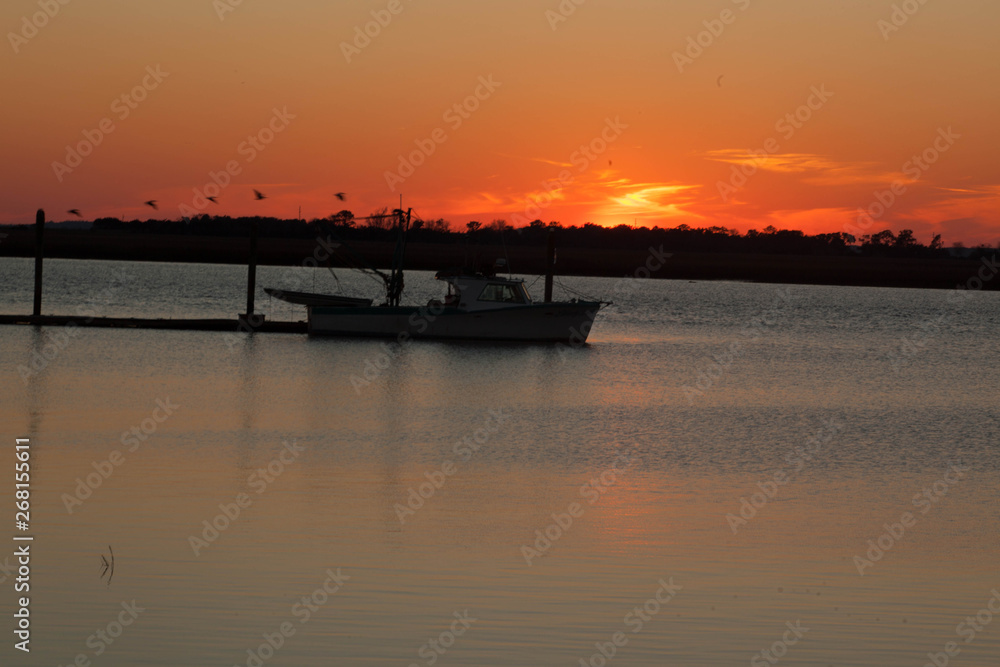 Sunset with a fishing boat moored to a dock