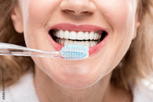 Cropped view of middle aged woman brushing Teeth Isolated On White