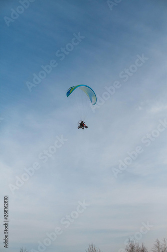 The paraglider flies over the clear blue winter sky. Free flight