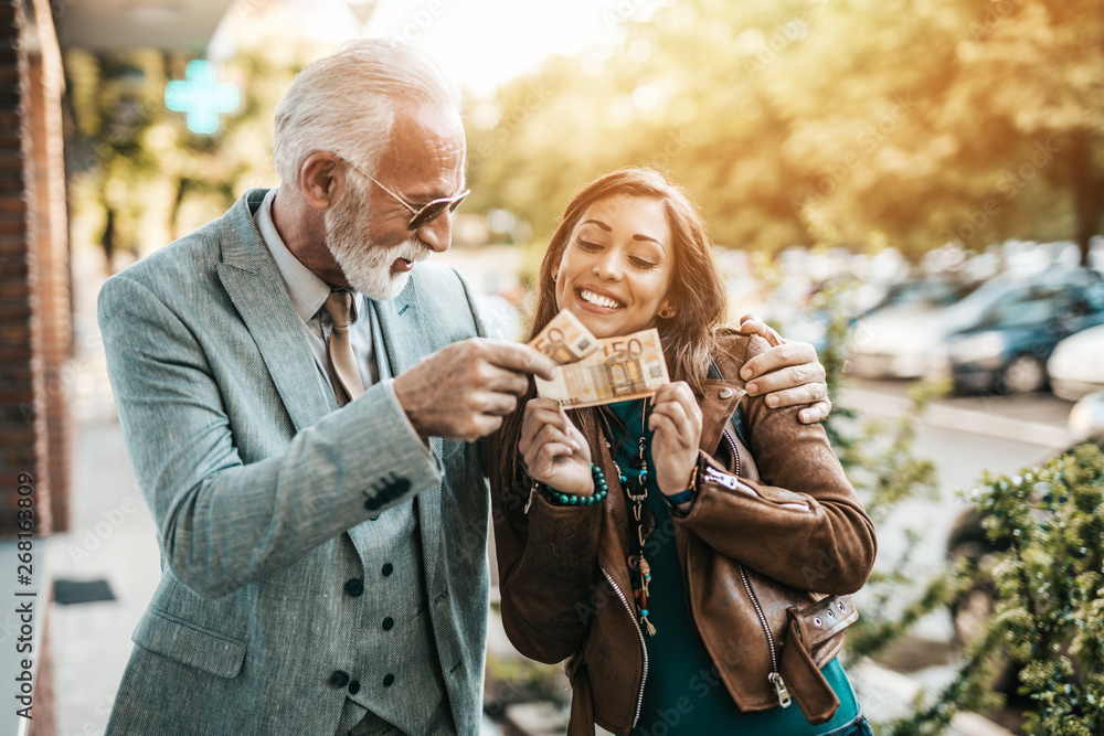 Senior father and his daughter using atm machine together to withdraw money. They are happy. Bright sunny day. Senior father and his daughter using atm machine together to withdraw money. They are happy. Bright sunny day.