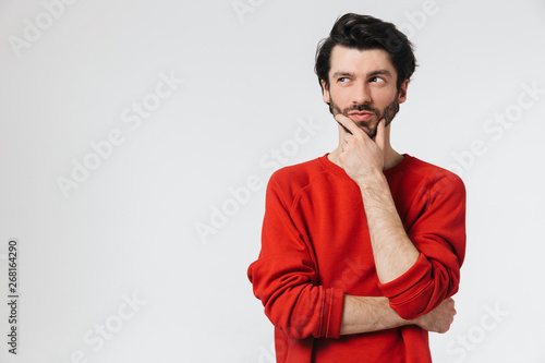 Handsome young thoughtful man posing isolated over white wall background.