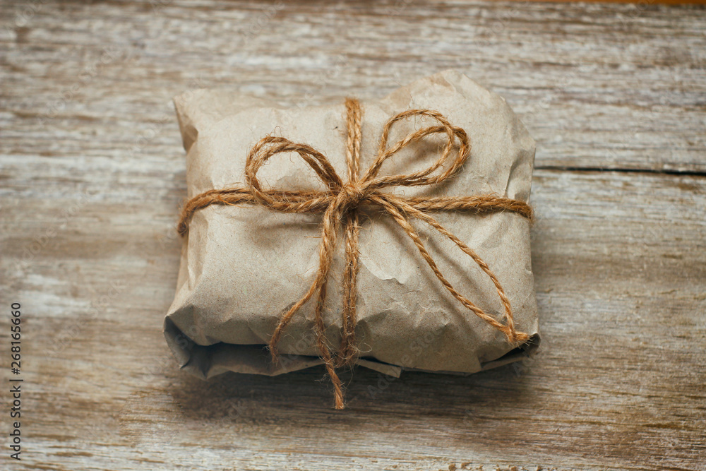Parcel box wrapped by brown craft paper. On wooden background. Delivery service. Parcel box wrapped by brown craft paper. On wooden background. Delivery service.