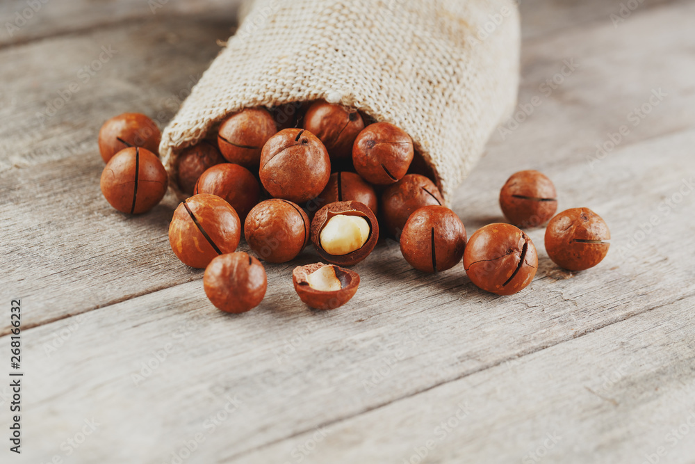 Macadamia nut on a wooden table in a bag, closeup, top view Macadamia nut on a wooden table in a bag, closeup, top view