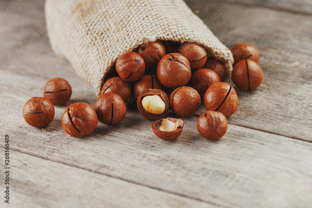 Macadamia nut on a wooden table in a bag, closeup, top view