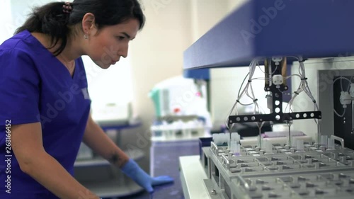 Portrait young lab assistant woman in blue uniform and rubber gloves controlling drug manufacturing in the laboratory. Conducting research in the lab. Science, profession, healthcare. Slow motion photo