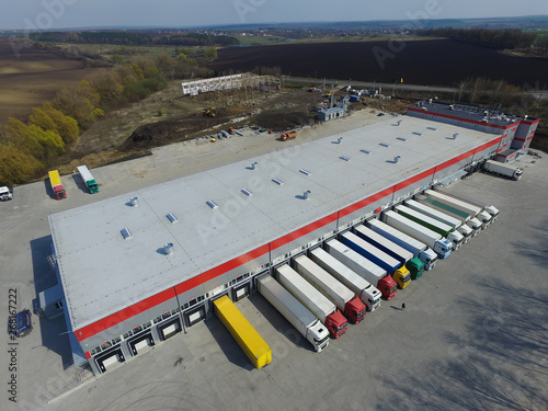 Aerial view of goods warehouse. Logistics center in industrial city zone from above. Aerial view of trucks loading at logistic center
