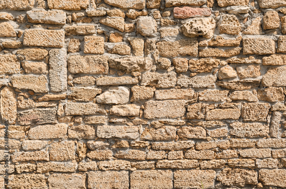 Fototapeta premium Old wall laid out in a chaotic manner of porous lime brick
