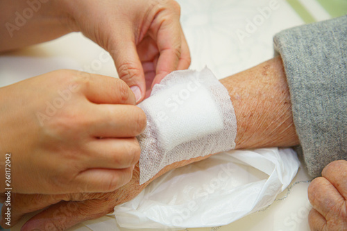 Fototapeta Close up old woman wrinkled skin hand, upper limb or arm to the wounded waiting for nurse treatment on wound dressing a bloody and brine of patient on white background