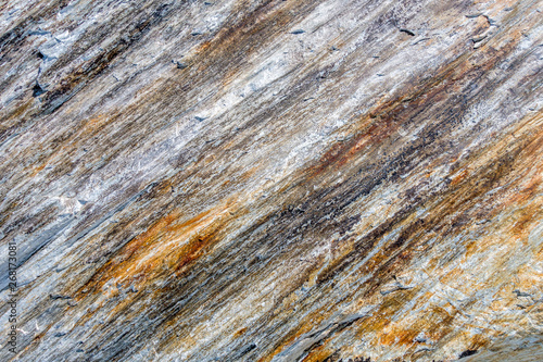 Multi-colored rock face with diagonal layers of iron deposits