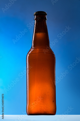 Beer bottle with white belgian ale on blue background