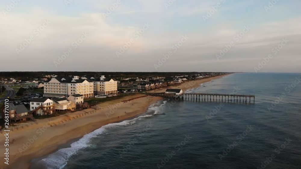 High, overhead aerial still Drone Shot of the North Carolina coast line with a view of the Kitty Hawk fishing pier and buildings on a overcast day. High, overhead aerial still Drone Shot of the North Carolina coast line with a view of the Kitty Hawk fishing pier and buildings on a overcast day.