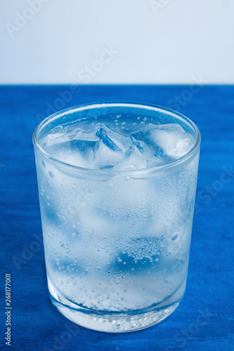  Transparent glass with water and ice cubes on a blue background