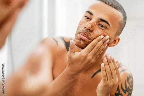 Obraz na plátně Handsome man applying natural scrub in front of a mirror