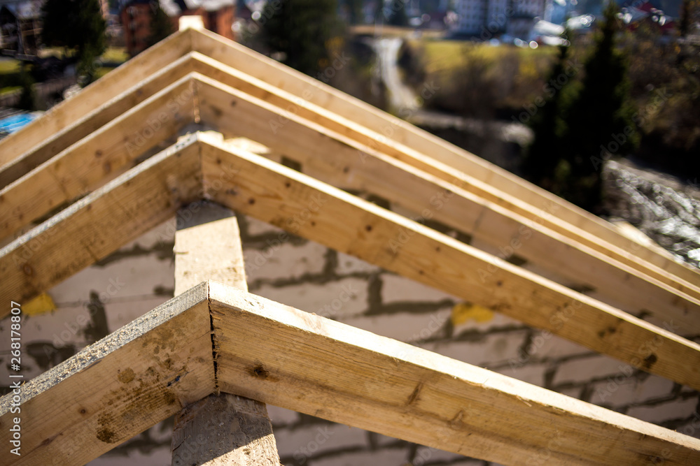 Close-up detail of roof frame of rough wooden lumber beams on background of misty mountain landscape in ecological area. Building, roofing, construction and renovation concept.