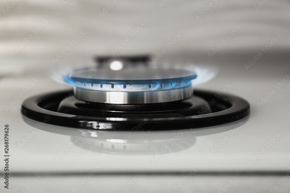 Gas burner with blue flame on modern stove, closeup Gas burner with blue flame on modern stove, closeup