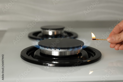 Woman lighting gas stove with match, closeup