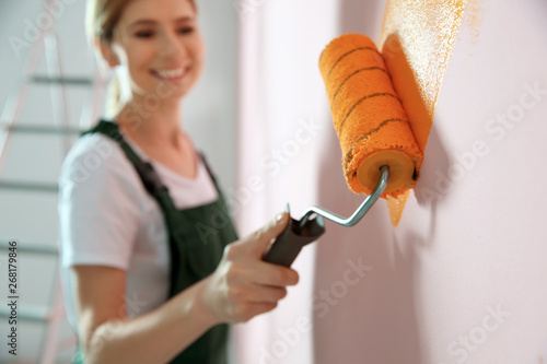 Professional decorator painting wall indoors. Home repair service photo