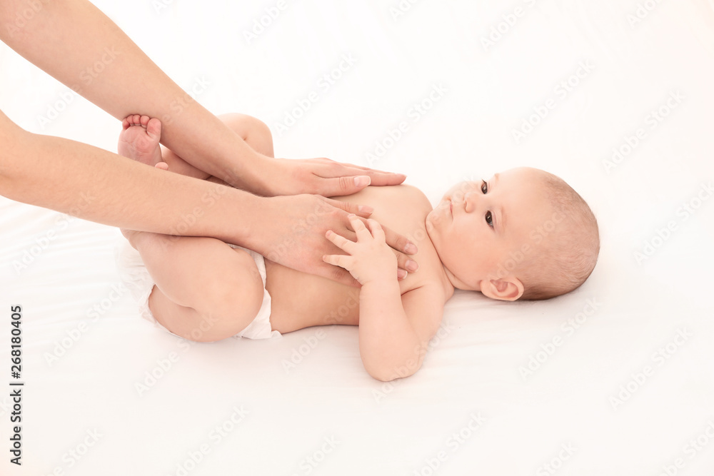 Mother and her cute child on white bed. Baby massage and exercises Mother and her cute child on white bed. Baby massage and exercises