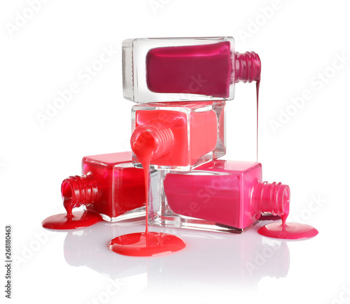 Spilled different nail polishes with bottles on white background